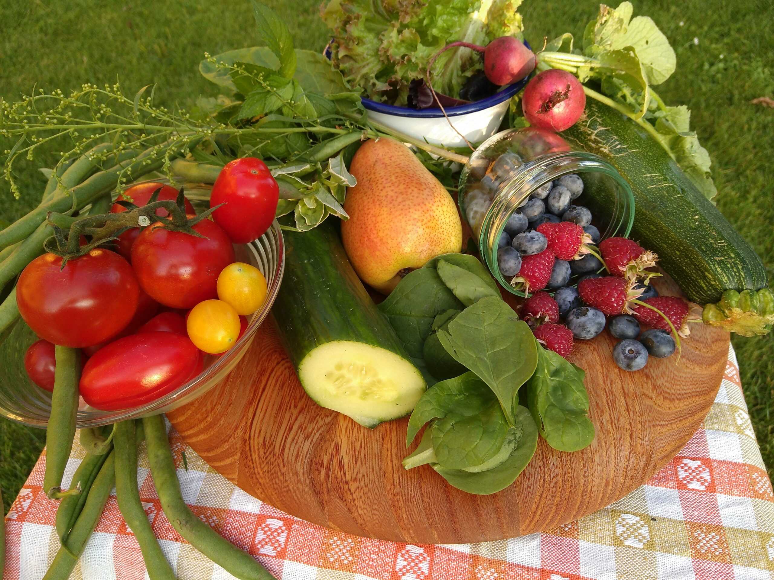 Das Foto zeigt ein Holzbrett beladen mit buntem Gemüse und Beeren.