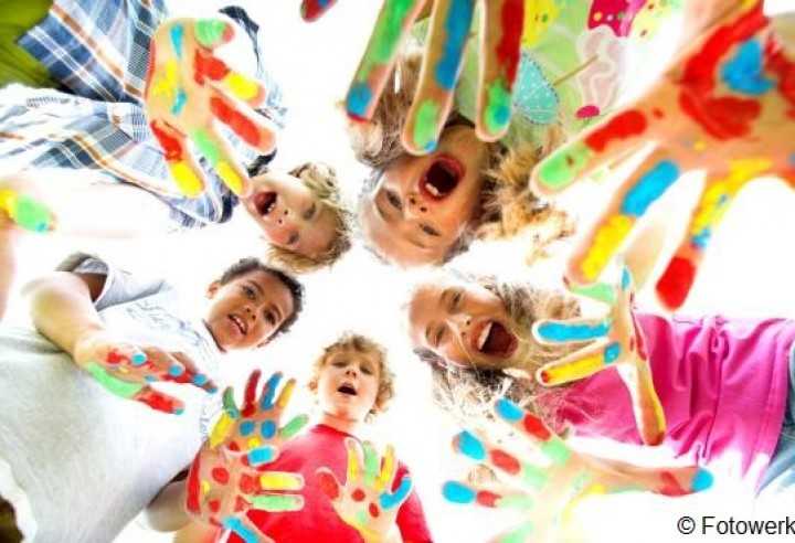 Das Foto zeigt eine Kindergruppe mit bunt angemalten Händen.