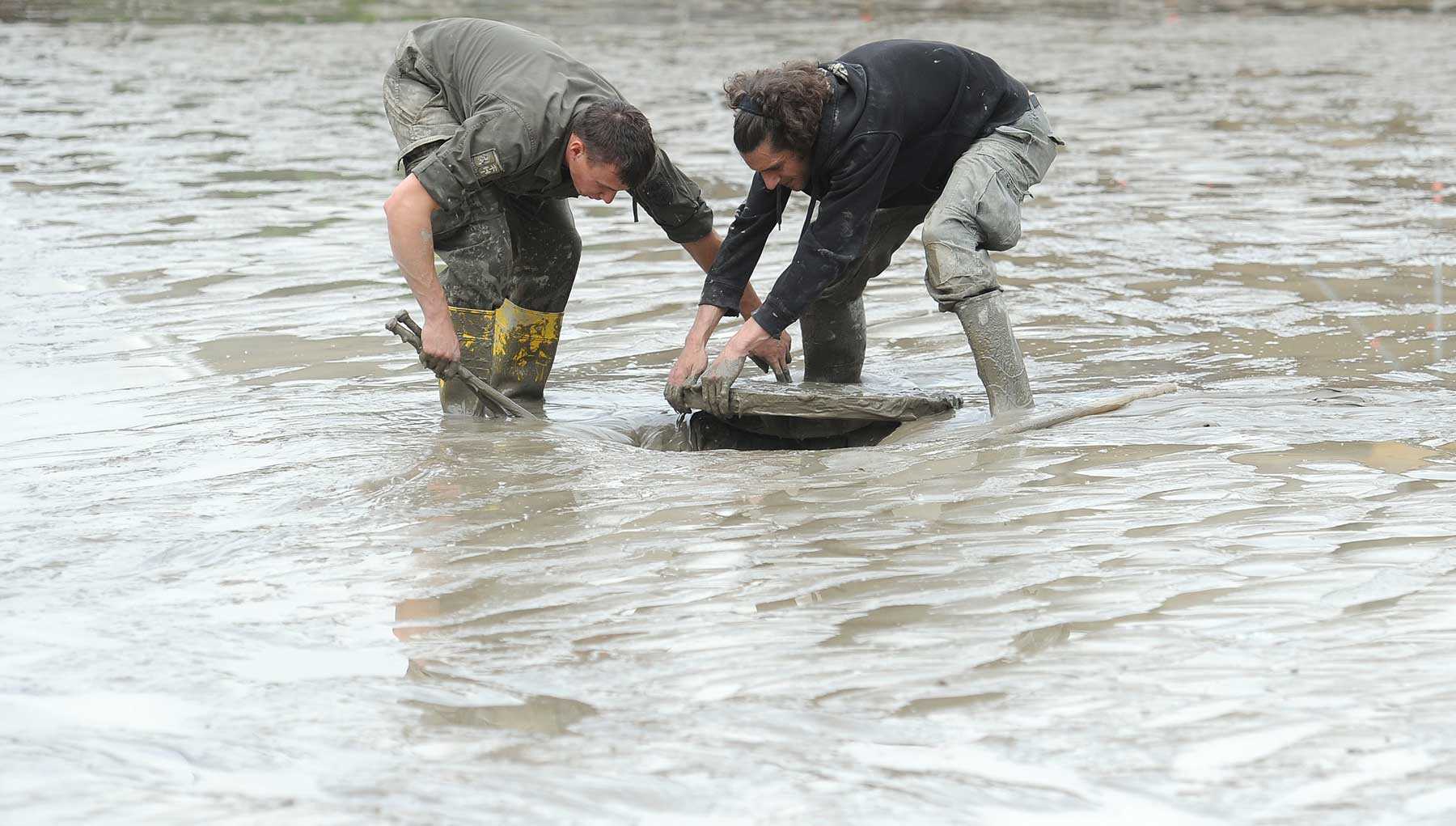 Das Foto zeigt einen Soldaten des Bundesheeres und einen Anrainer am Freitag, 7. Juni 2013, bei Aufräumungs- und Säuberungsarbeiten am Gelände der Wachauarena in Melk. Starkregen prägt mittlerweile die Sommer vieler Gemeinden.